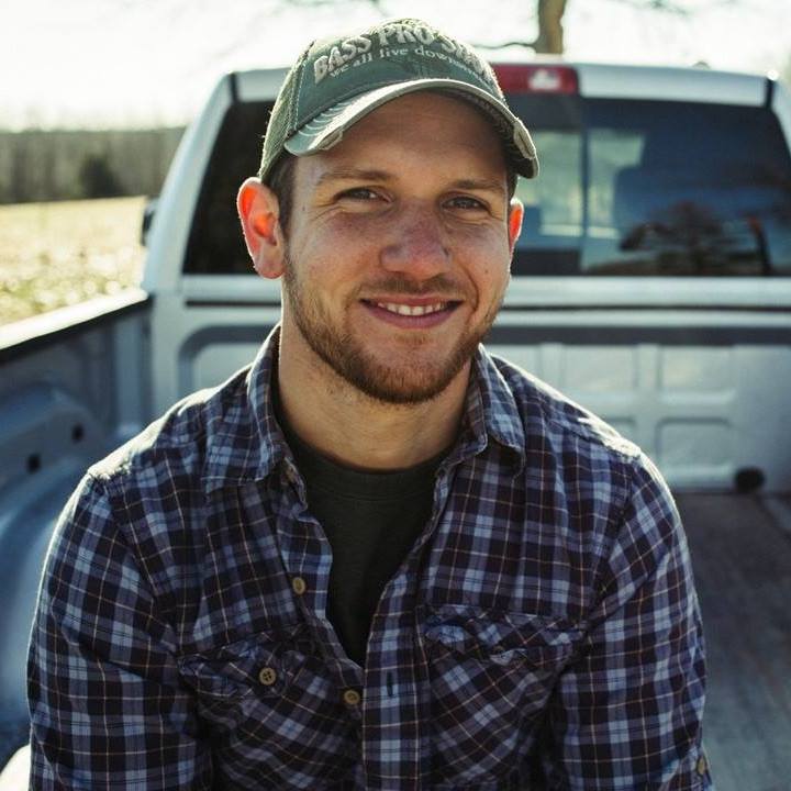 Matt dye sits on the back of a pickup truck in a field